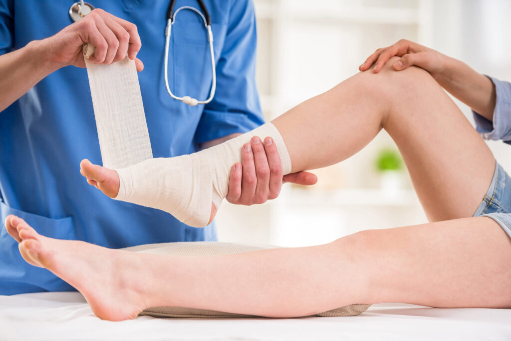 Close-up,Of,Male,Doctor,Bandaging,Foot,Of,Female,Patient,At