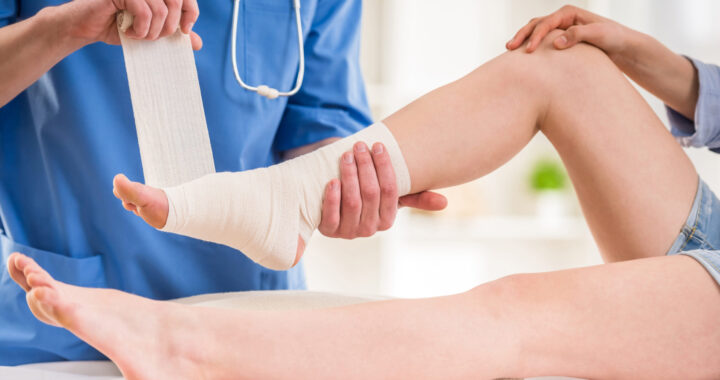 Close-up,Of,Male,Doctor,Bandaging,Foot,Of,Female,Patient,At